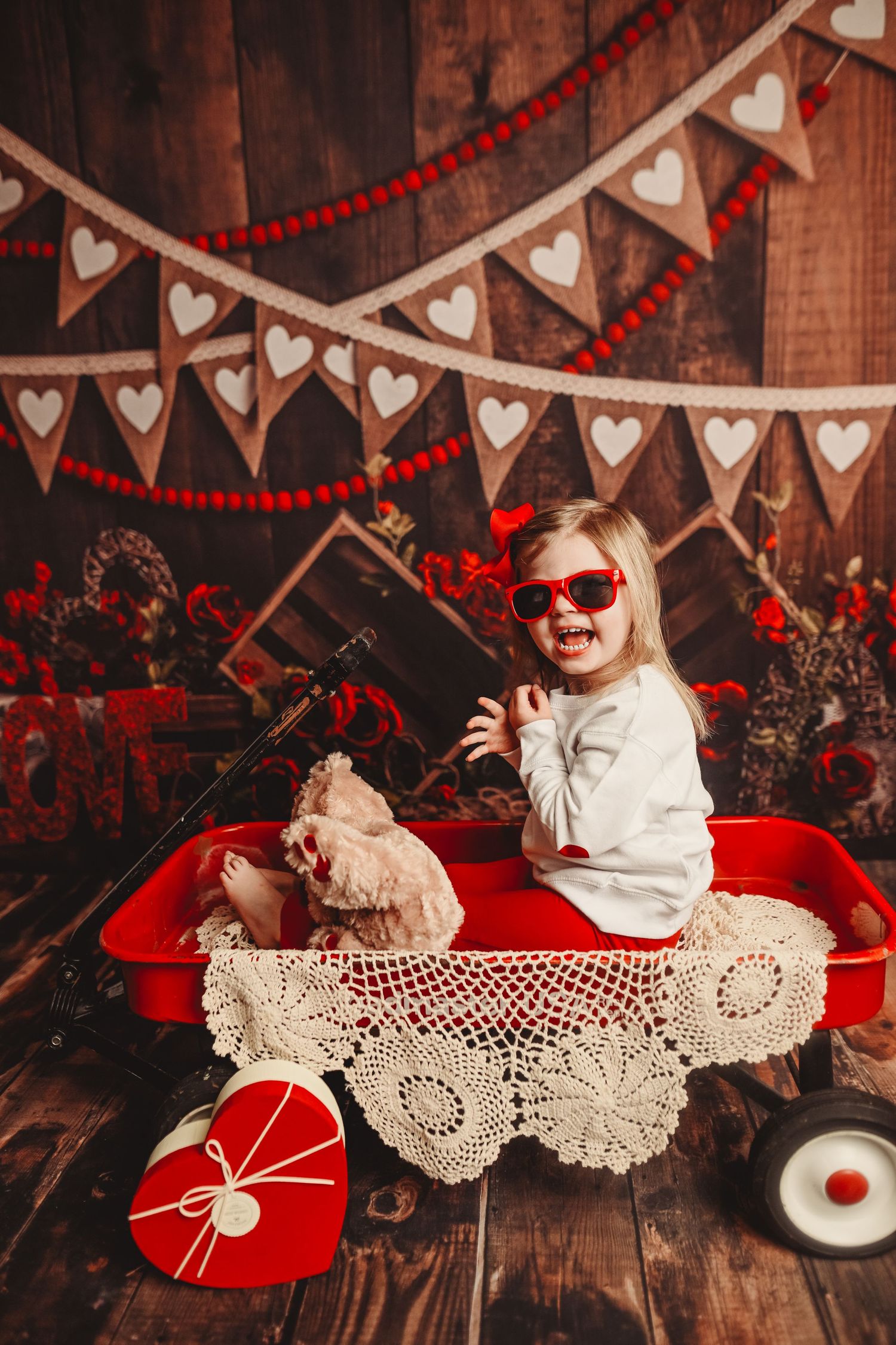 Valentine's day themed setup with red hearts and lace decorations on wooden background.