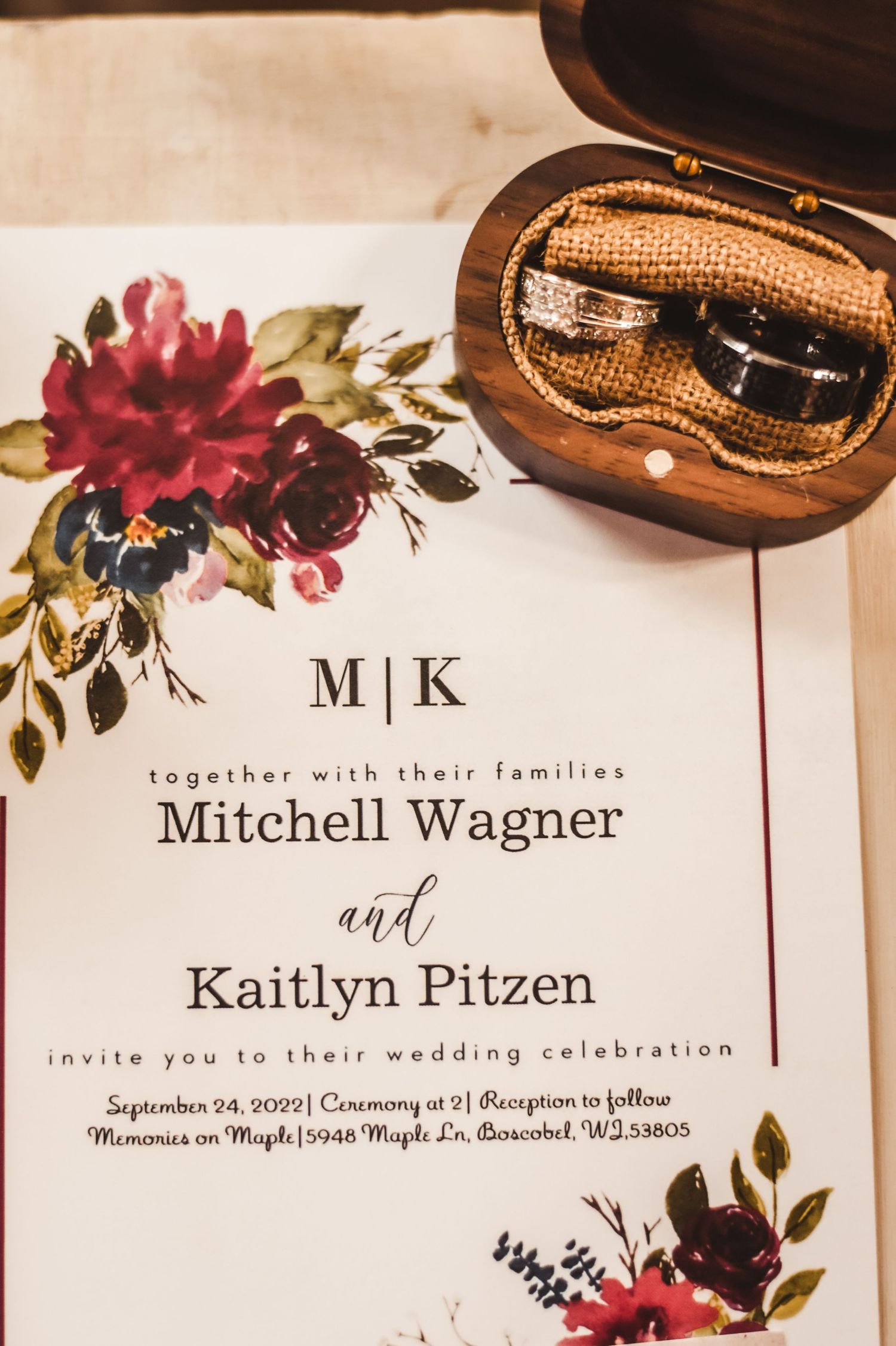 Floral wedding invitation with wedding rings in wooden box.