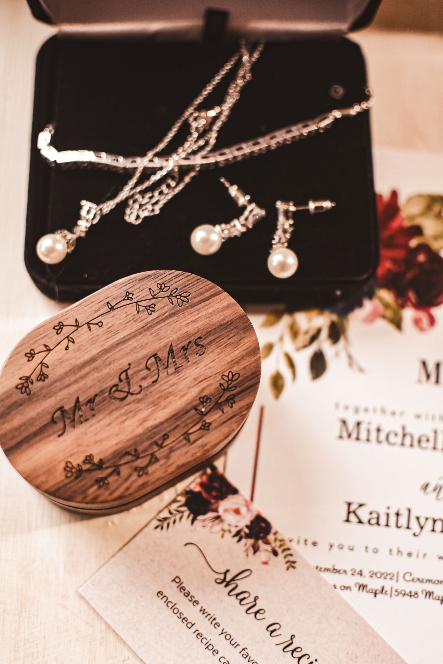 Pearl jewelry set and wooden ring box displayed with wedding invitation.