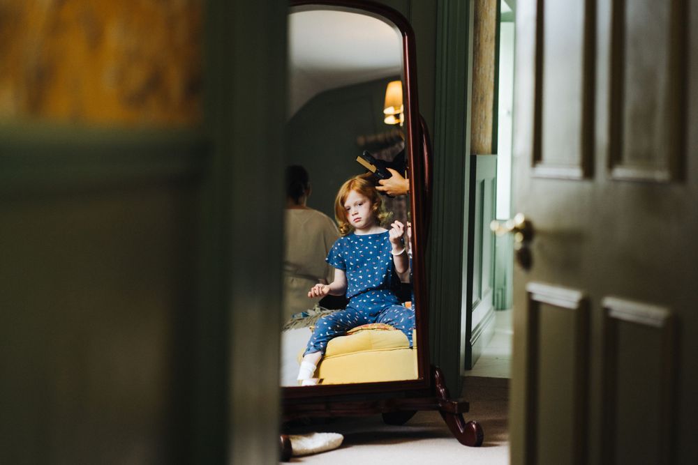 A child in a blue dress seen through a doorway.