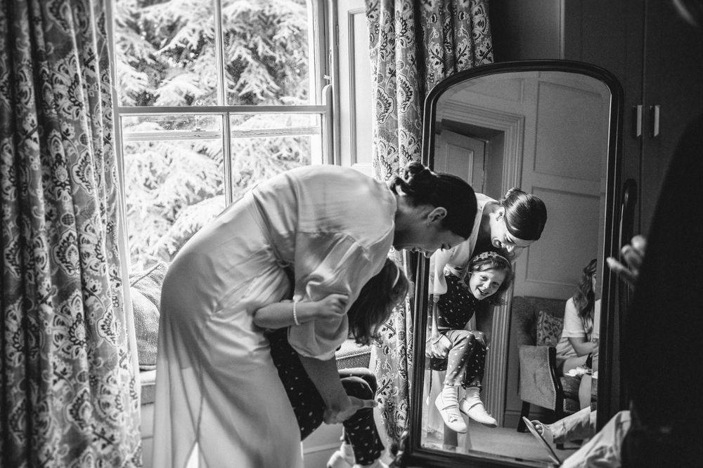 A wedding preparation scene captured in black and white through an open doorway.
