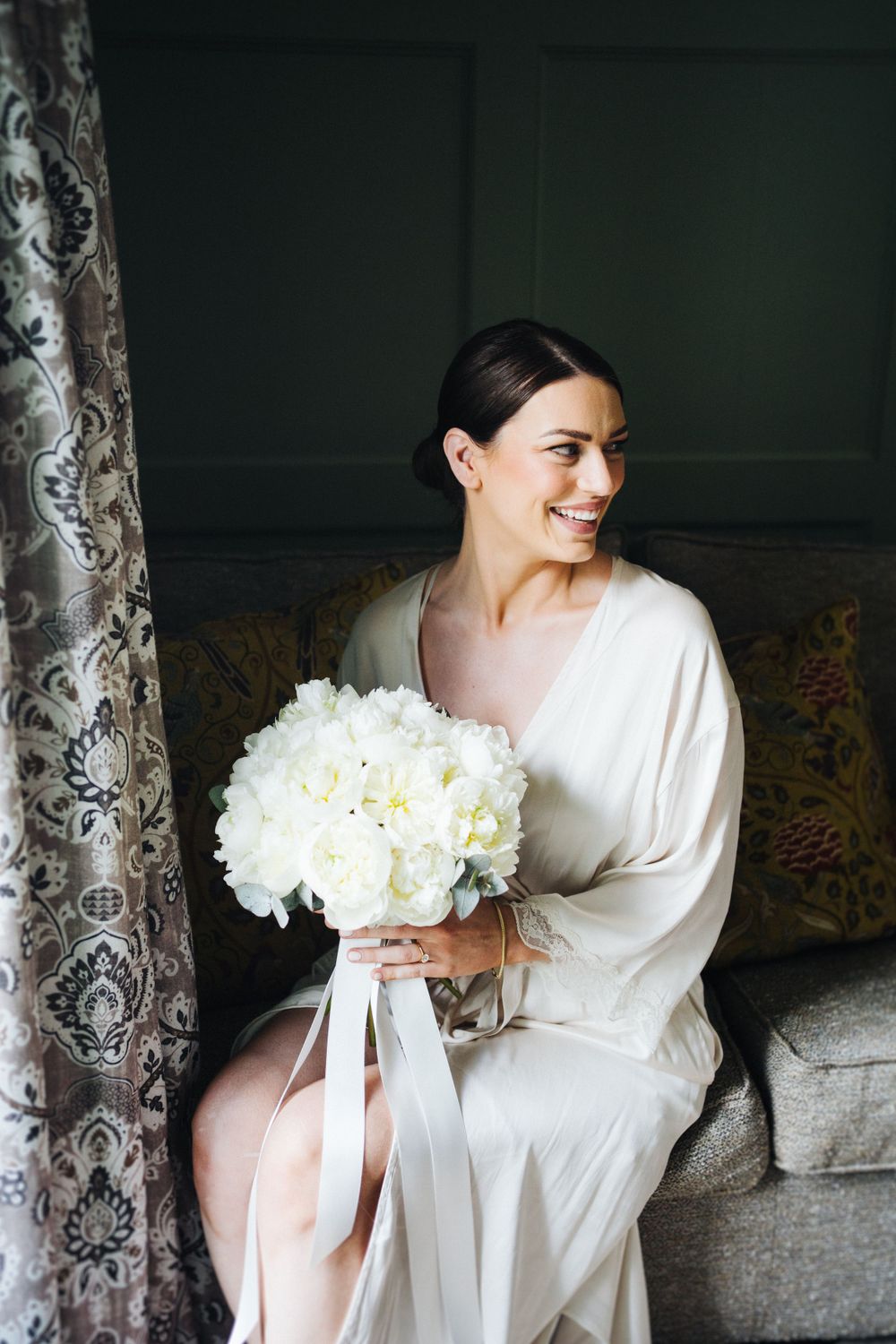 A person in white holds a beautiful bouquet of white flowers against an elegant backdrop.