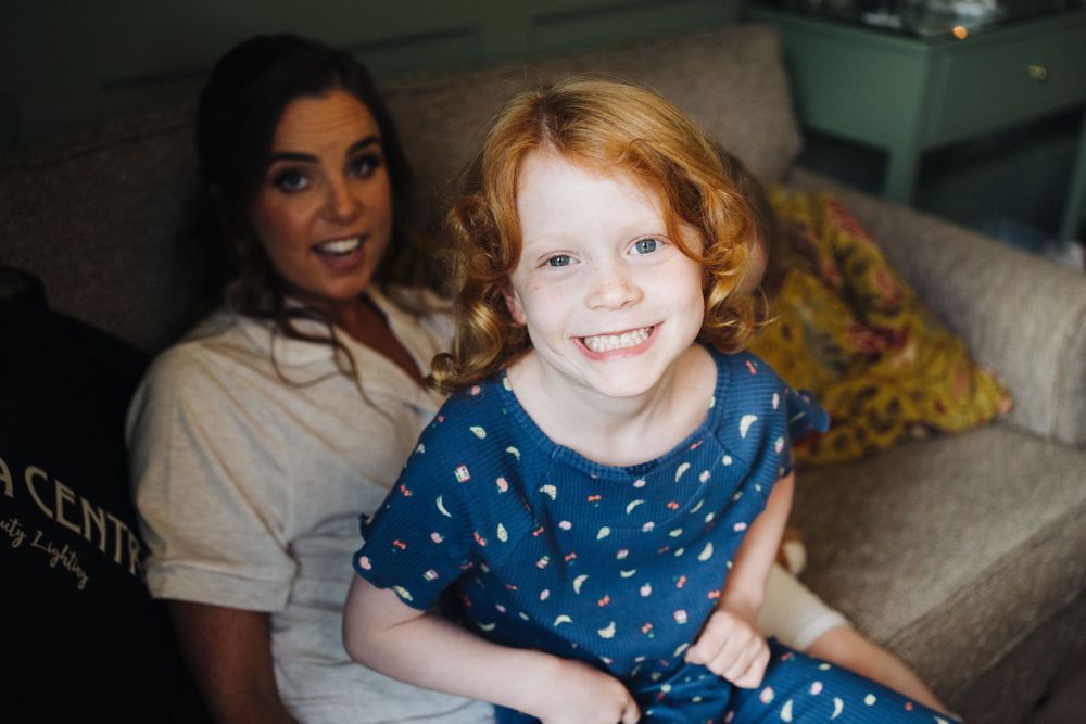 Candid moment with young child in polka dot dress sitting on couch.
