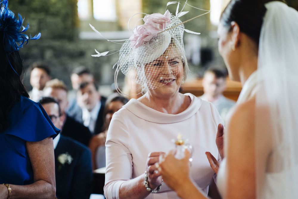 Wedding guest wearing pale pink fascinator hat during outdoor celebration.