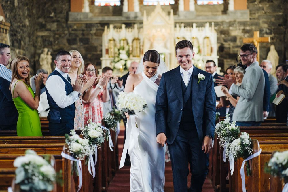 Wedding ceremony recessional in a historic church with guests celebrating along the aisle.