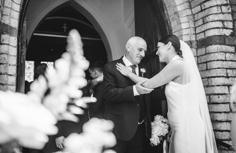 Black and white photo of greeting guests outside a church's arched entryway.