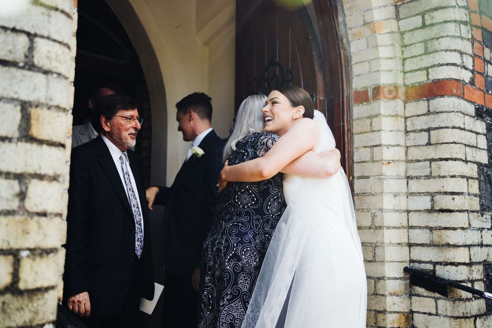 Emotional hugs and greetings outside a brick church entrance after the ceremony.