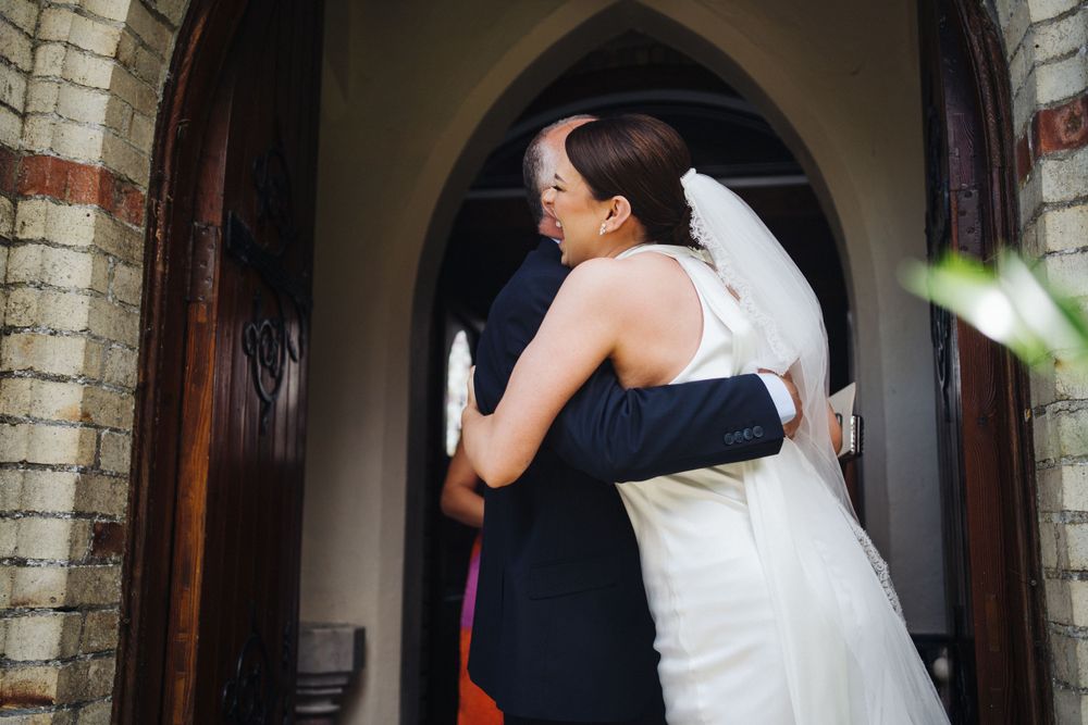 A tender embrace shared in a church doorway with gothic arched architecture.