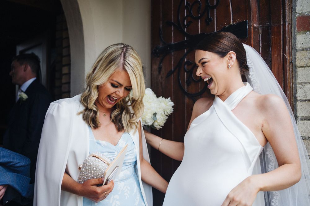 Wedding guests in formal attire share a lighthearted moment near an arched doorway.