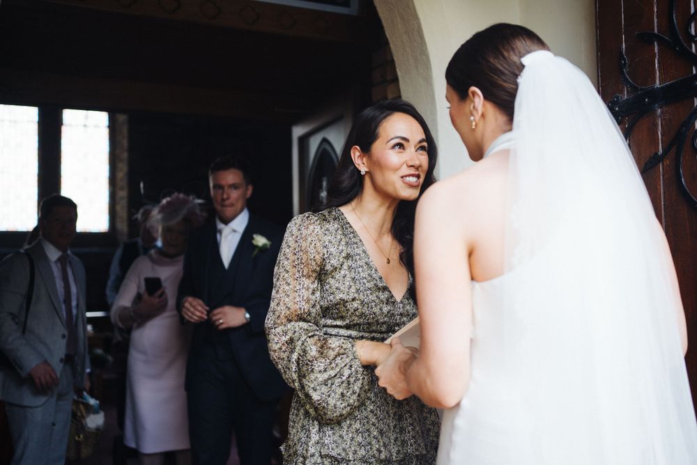 Wedding attendees share a warm conversation in formal attire at church entrance.