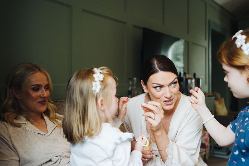 A group gathers during wedding preparations in a room with green walls.