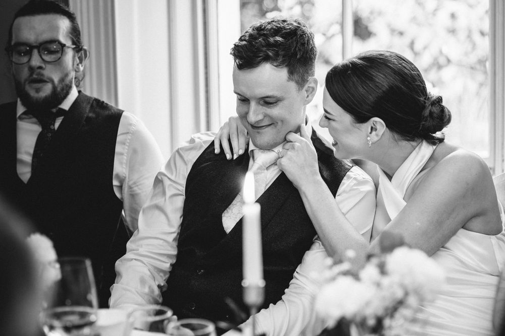Black and white candid moment of wedding reception conversation.