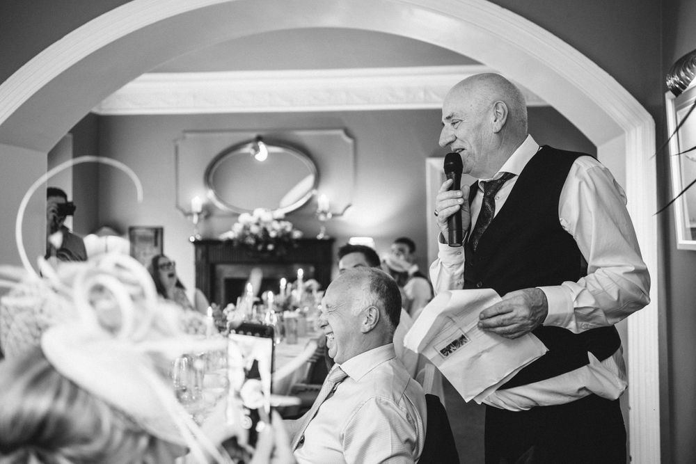 A waiter serves guests during an indoor wedding reception in black and white photography.