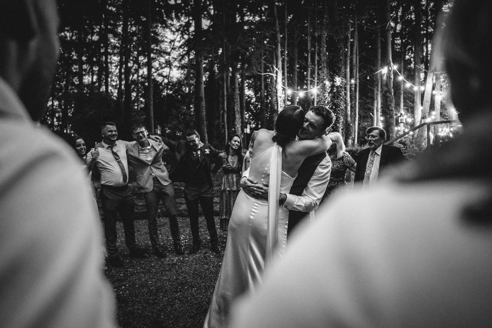 Intimate first dance moment captured in black and white at an outdoor forest wedding reception.