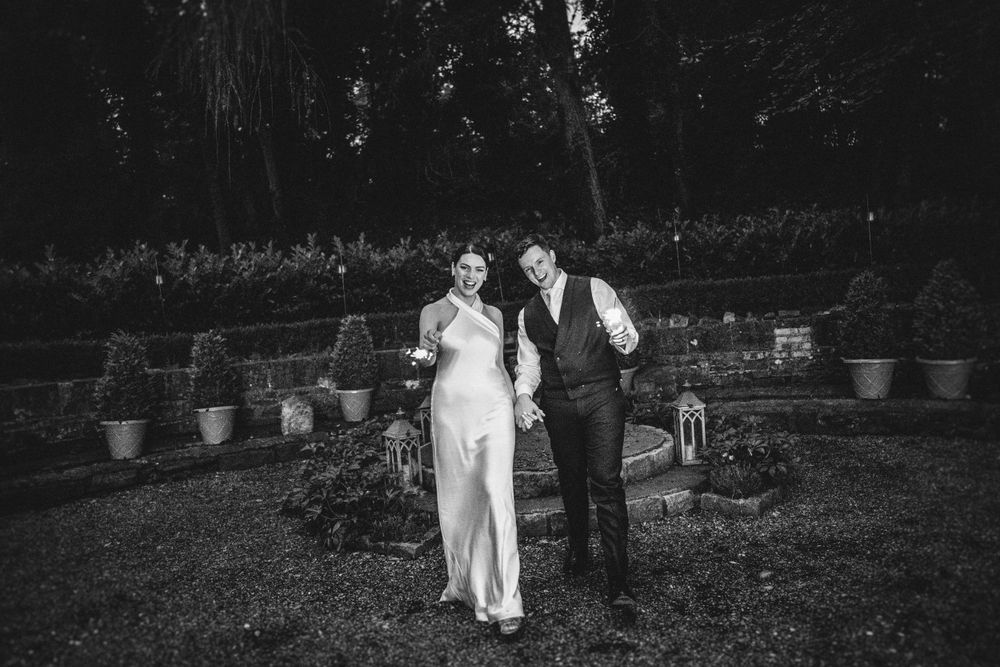 Couple walks together through a garden setting at their outdoor wedding.