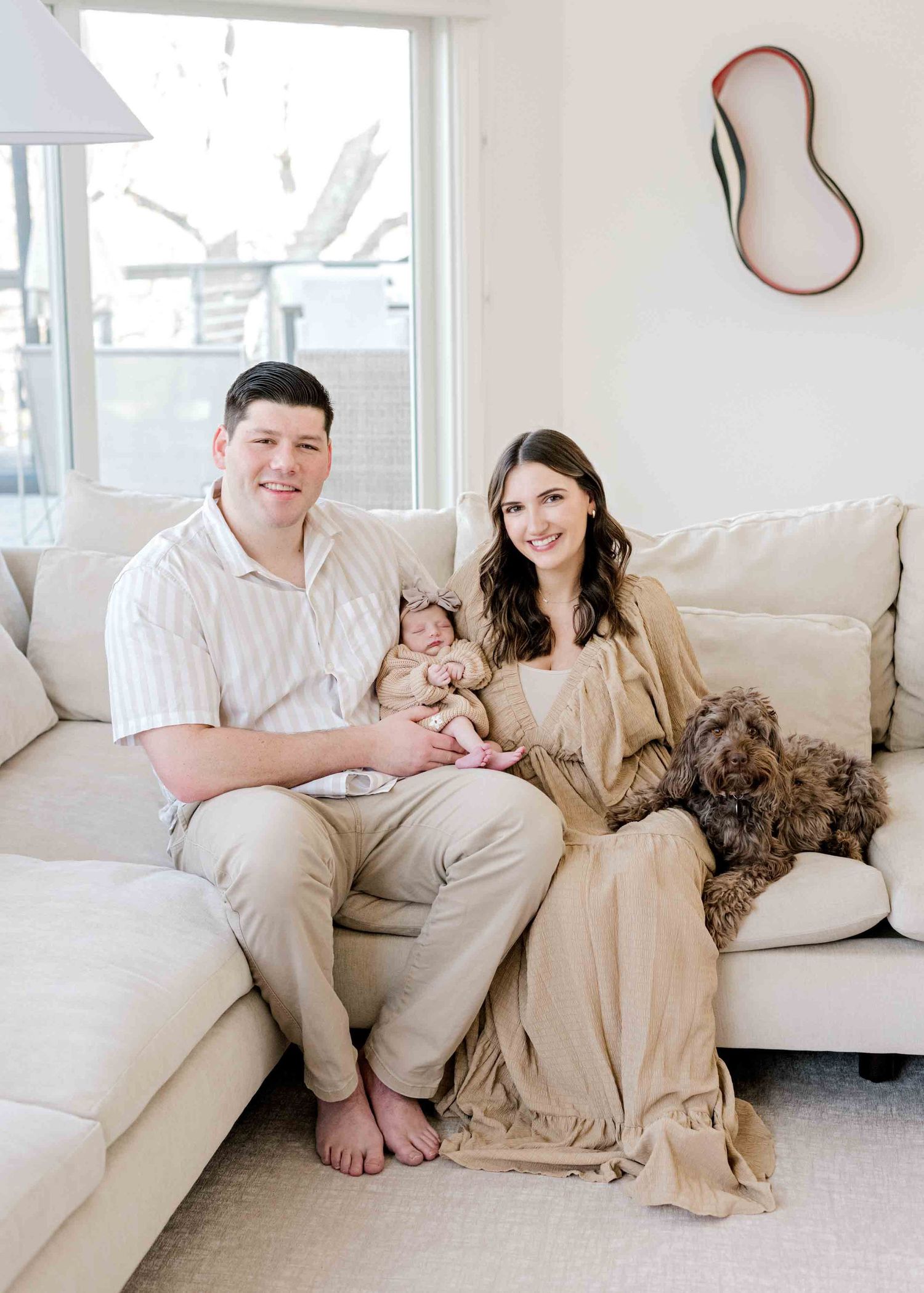 Modern family portrait in a bright living room with their pet dog.