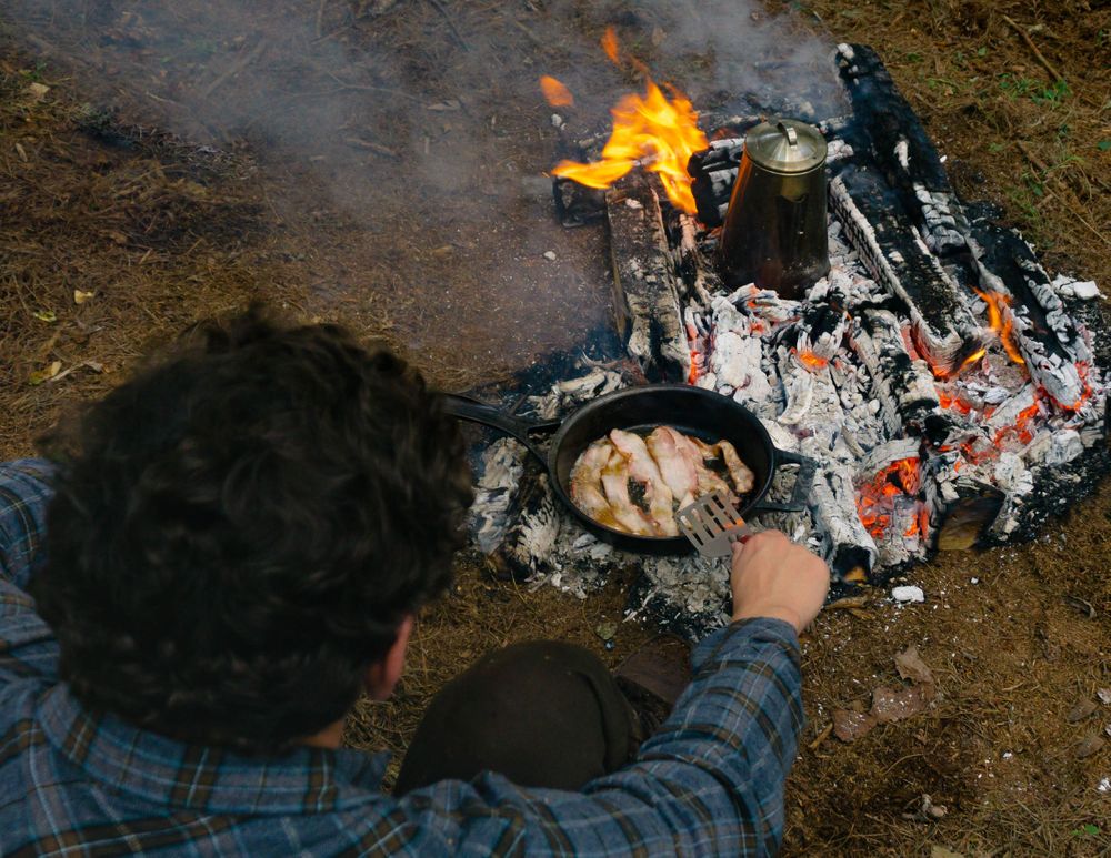 cooking bacon in a stargazer cast iron skillet over a campfire