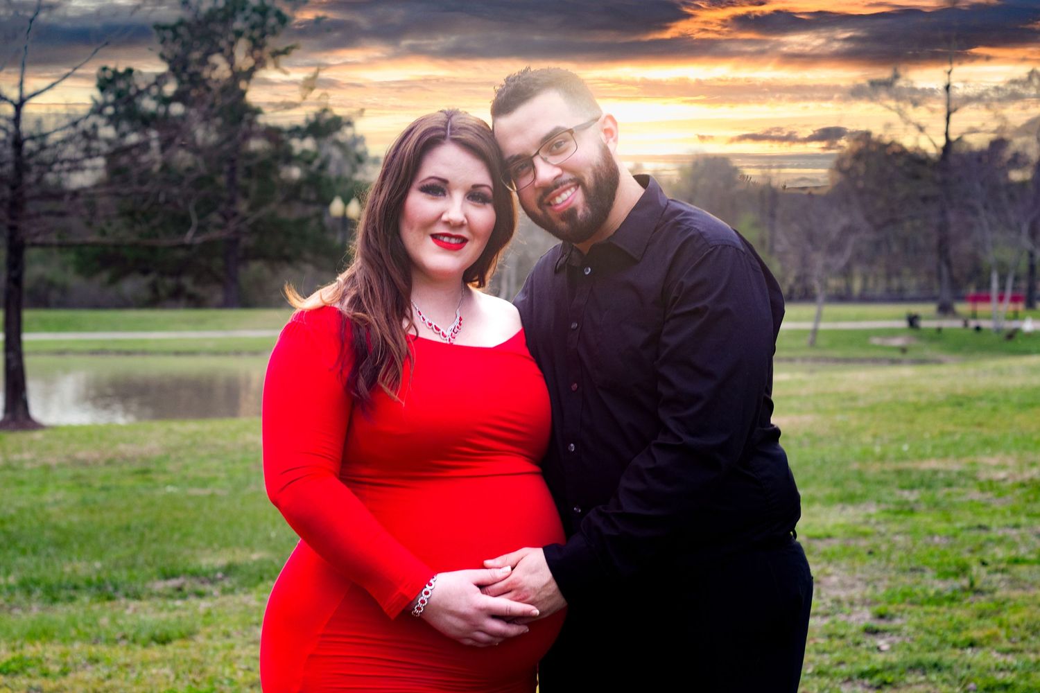 A couple in matching red and black outfits embrace during a romantic outdoor photoshoot at sunset.