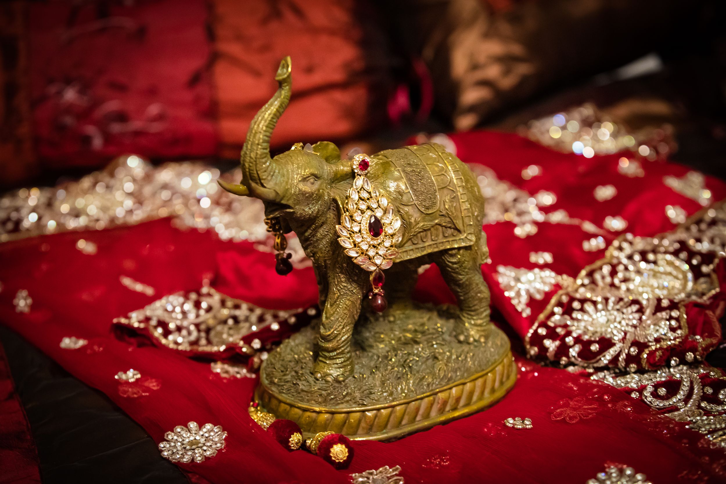 Traditional Indian wedding jewelry and decorative items displayed on red velvet fabric.