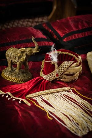 Traditional Indian wedding accessories and golden decorations on red velvet cloth.