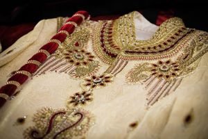 Ornate gold and cream embroidered traditional Indian wedding attire with intricate beadwork details.