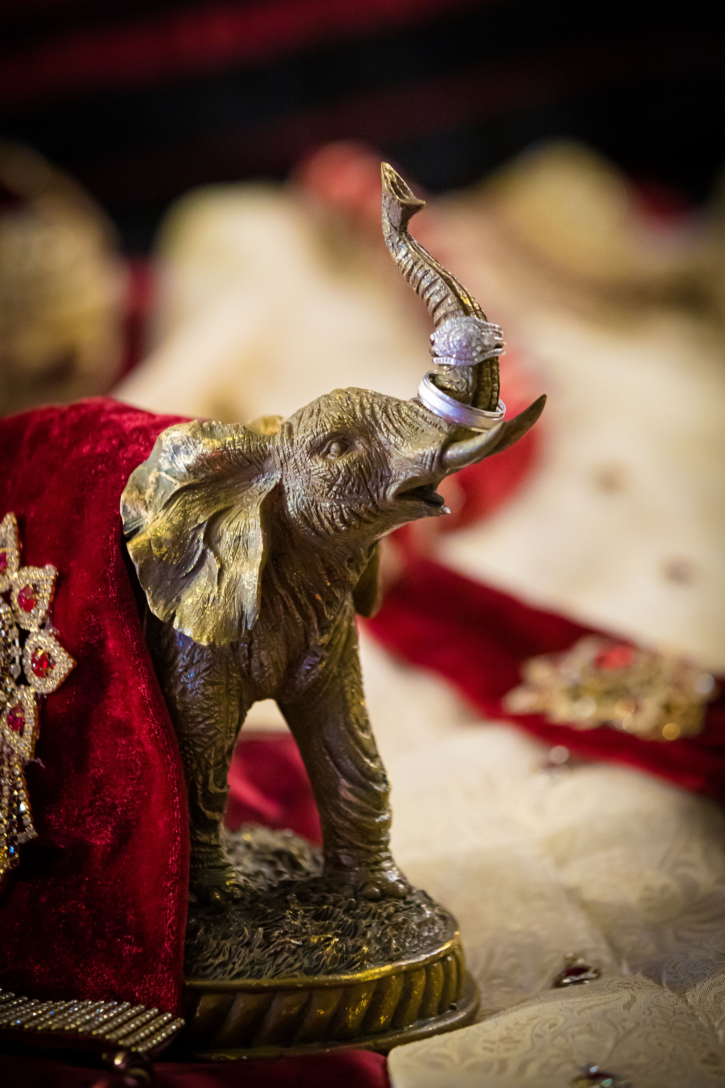 Golden elephant figurines displayed on textured fabric for Indian wedding ceremony.