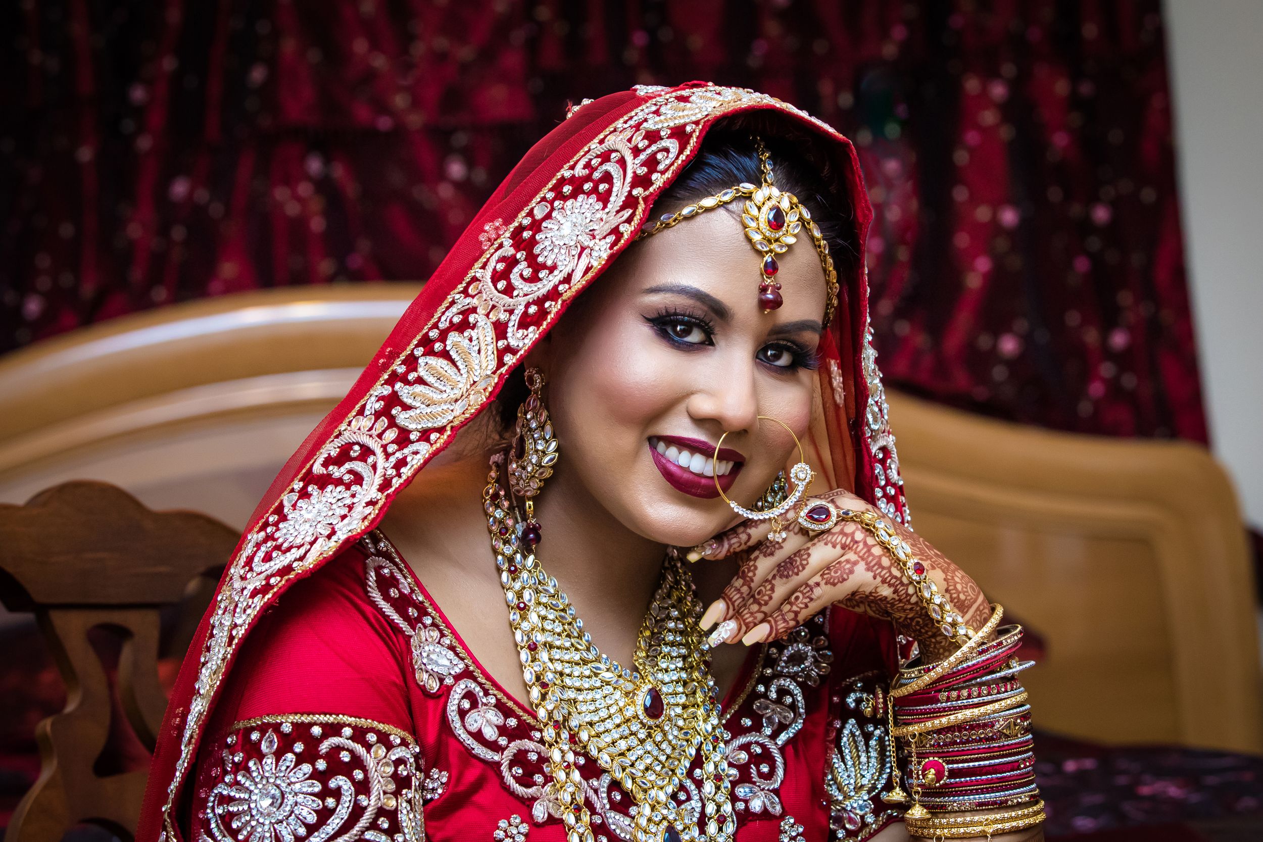 Close-up of traditional Indian bridal jewelry and red embroidered fabric with delicate details.