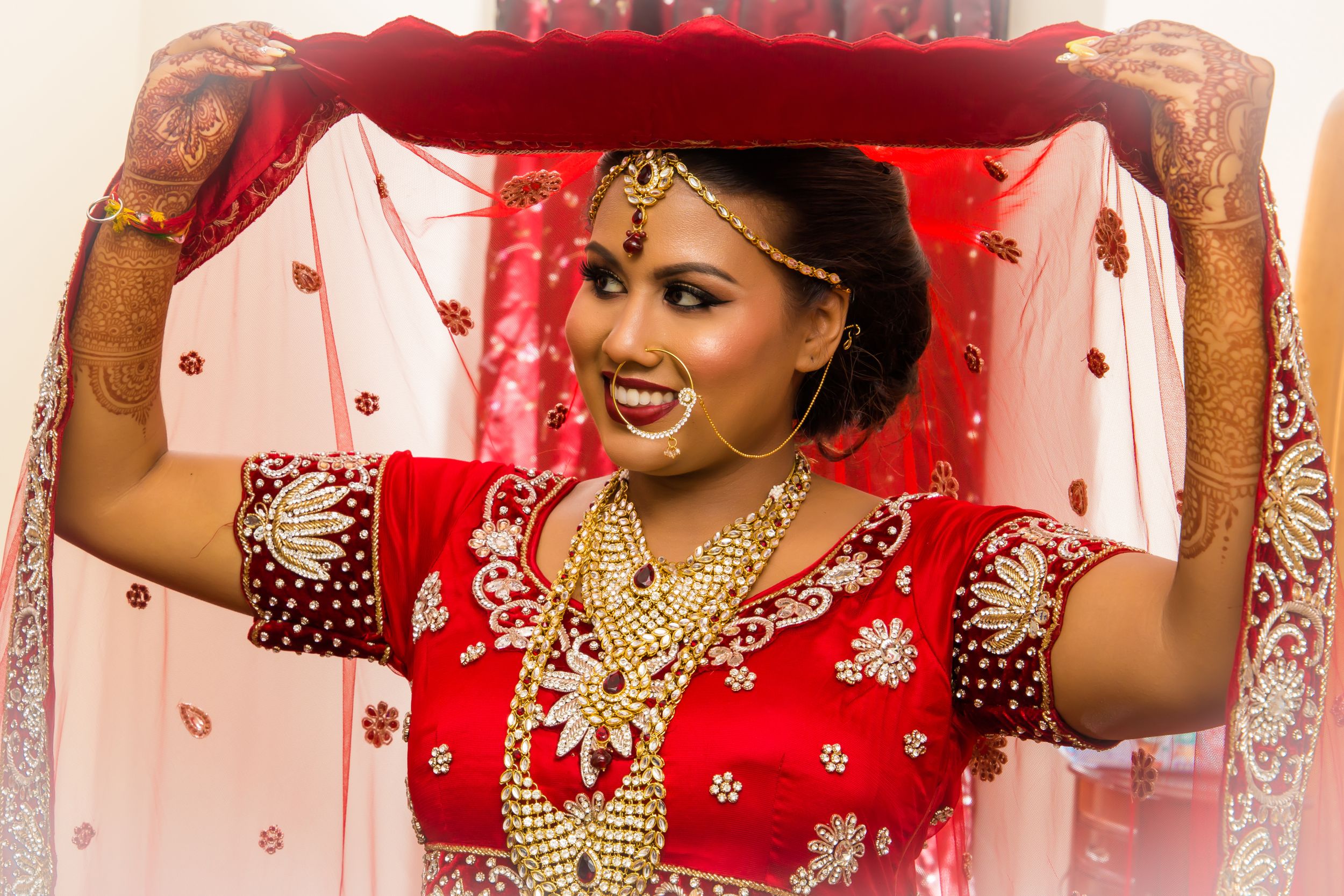 Festive Indian wedding attire with bright red fabric and traditional decorative elements.