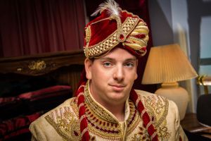 Side profile of groom wearing luxurious cream and gold wedding attire.