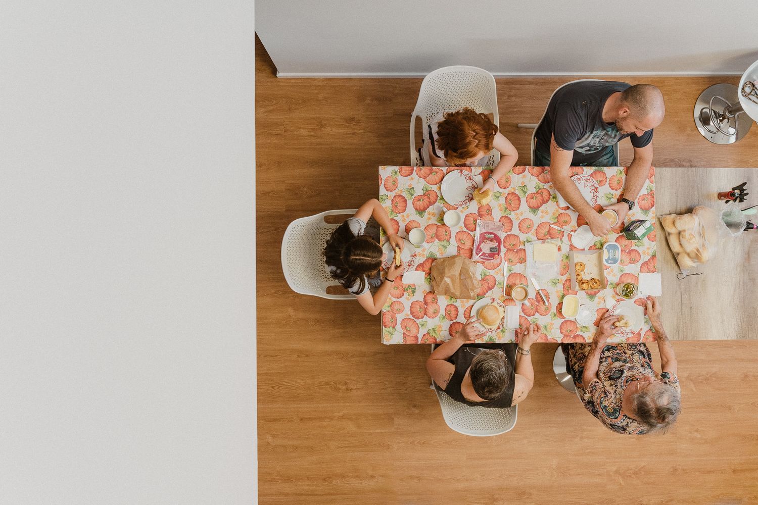 Overhead view of a table with people sharing a meal together on a wooden surface.