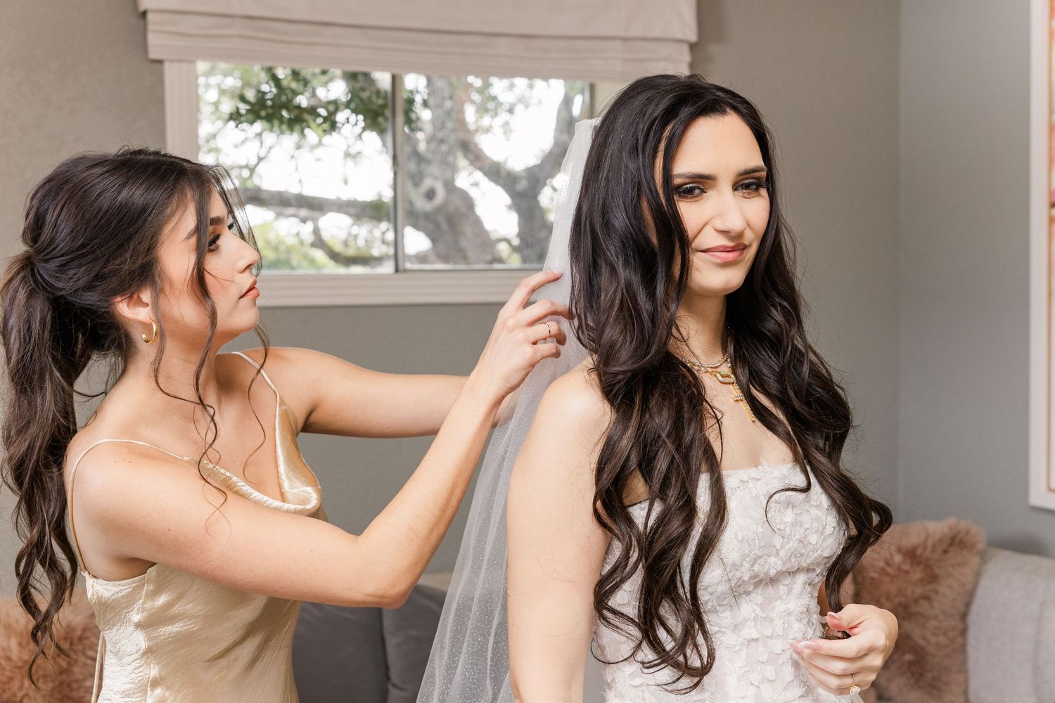 maid of honor putting veil on bride