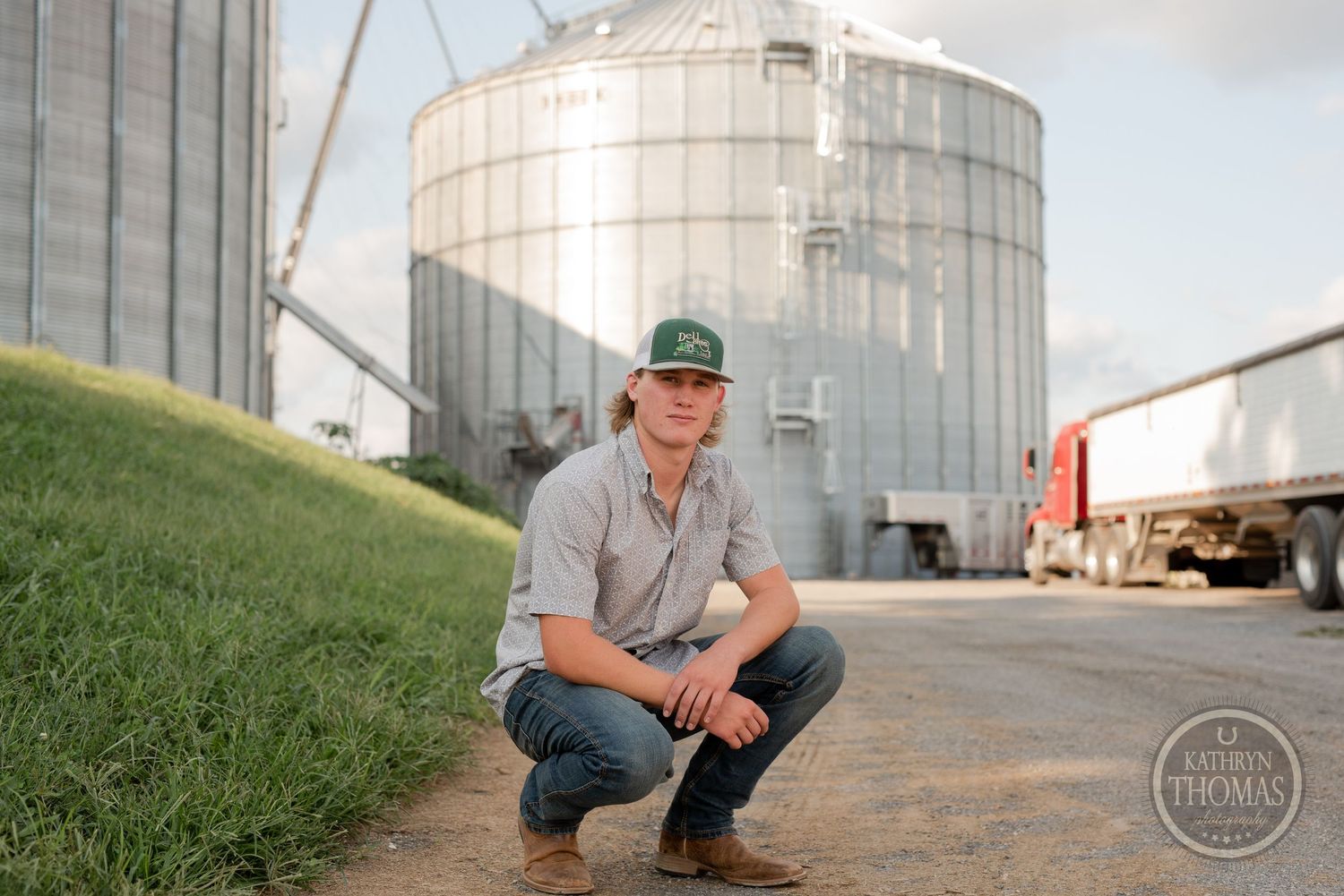 View near grain storage silos showing agricultural equipment and equipment in background.