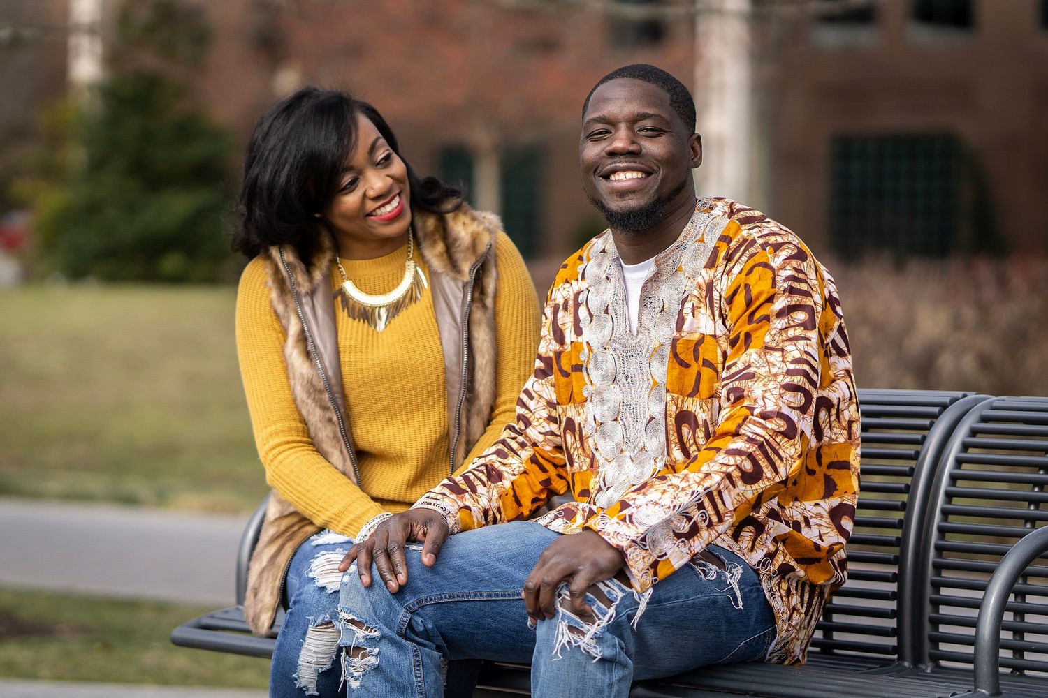 A couple sharing a lighthearted moment while sitting together on a park bench.