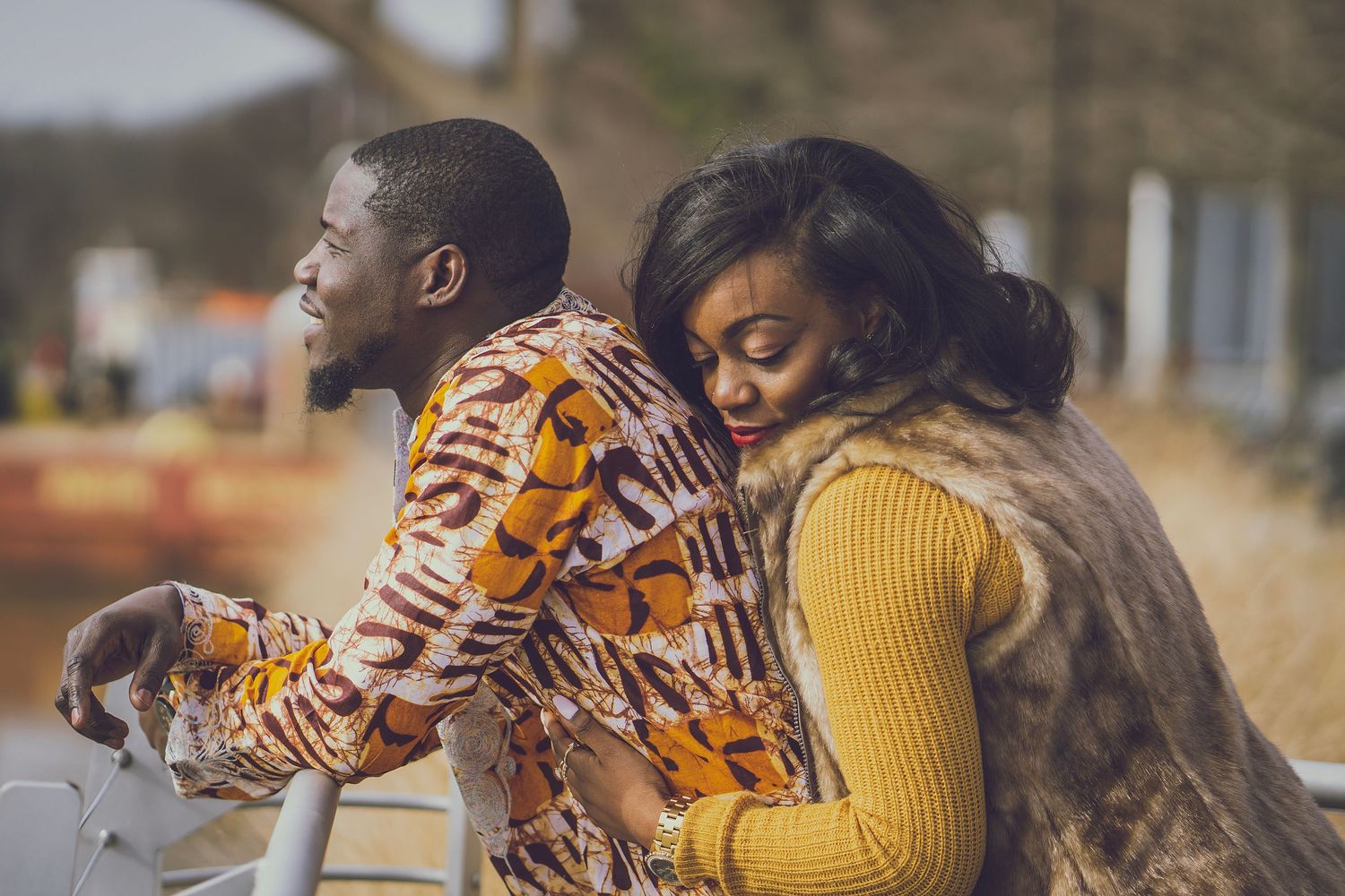 A couple in coordinated outfits share a playful moment while leaning against a railing.
