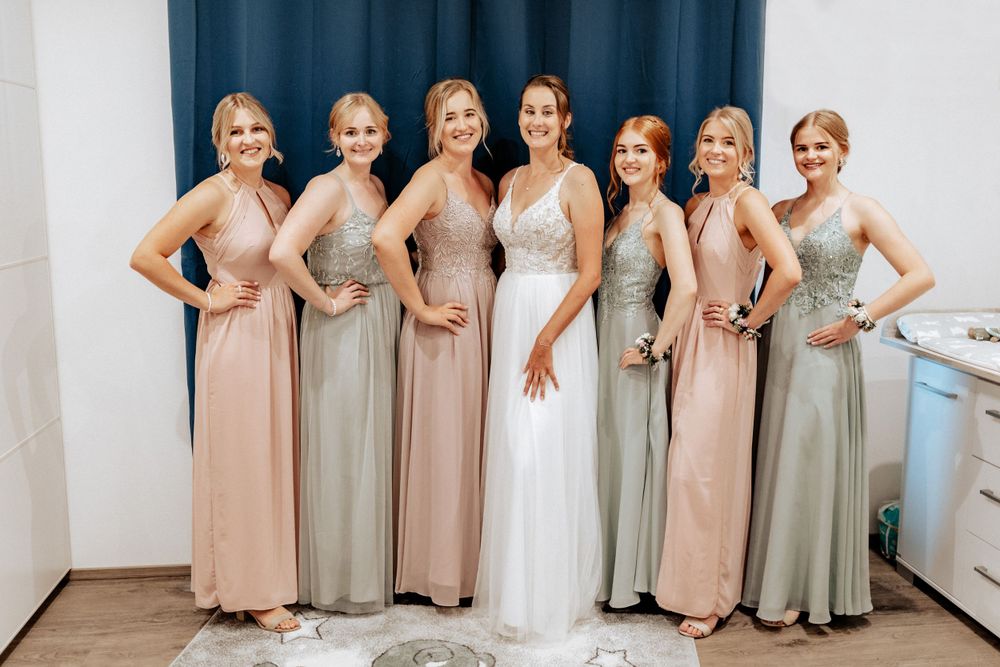 Wedding party poses in alternating blush and sage colored dresses.
