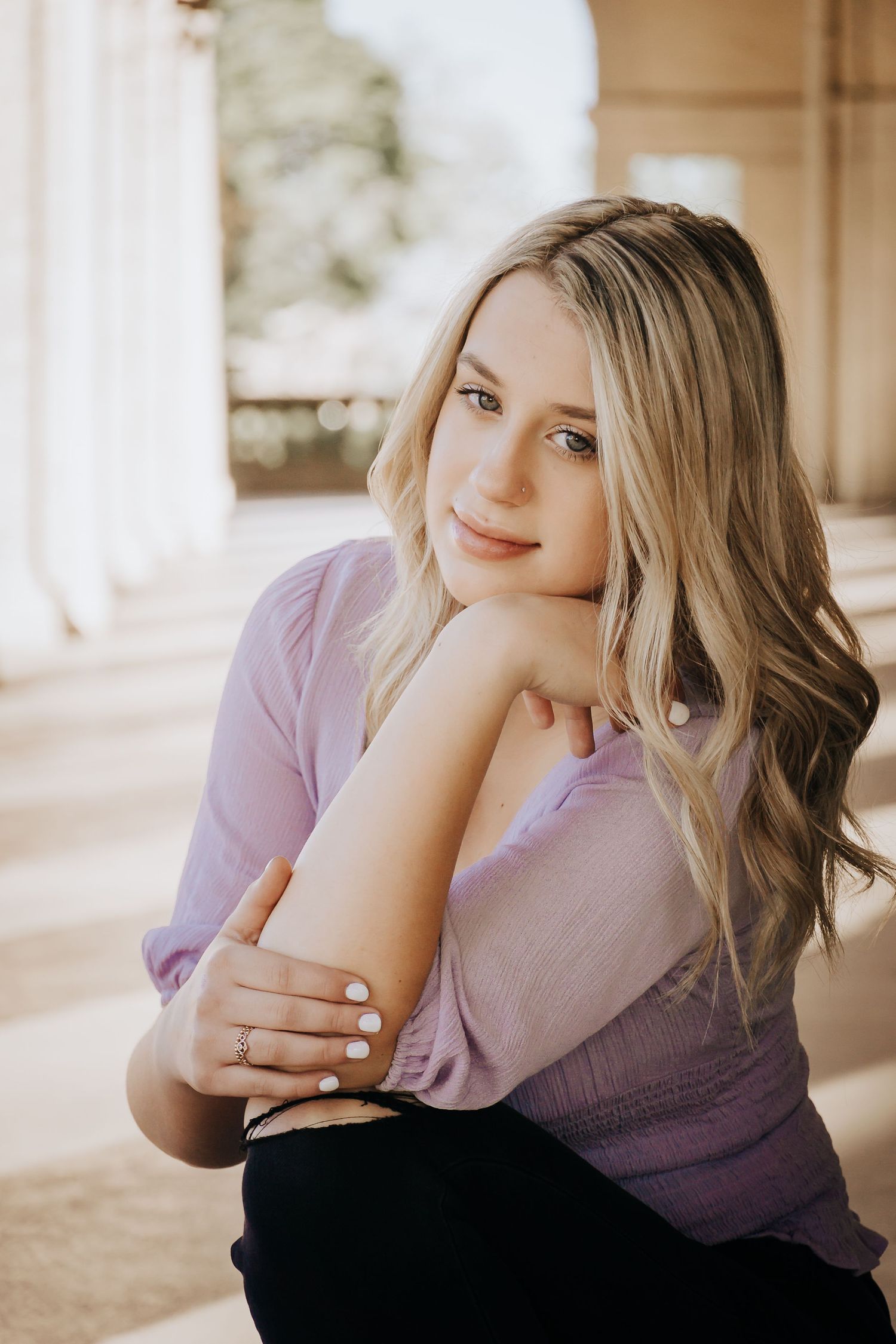 Portrait of a blonde woman in lavender sweater sitting in warm natural light.