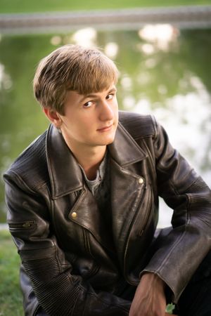 Portrait of person in black leather jacket against blurred nature background.