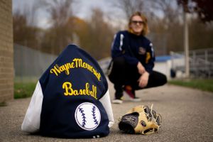 Baseball equipment including navy jacket and glove on concrete ground.