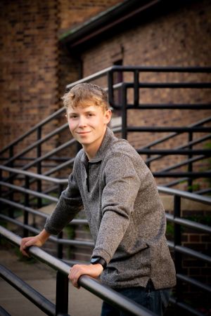 Portrait on metal staircase against brick building backdrop.