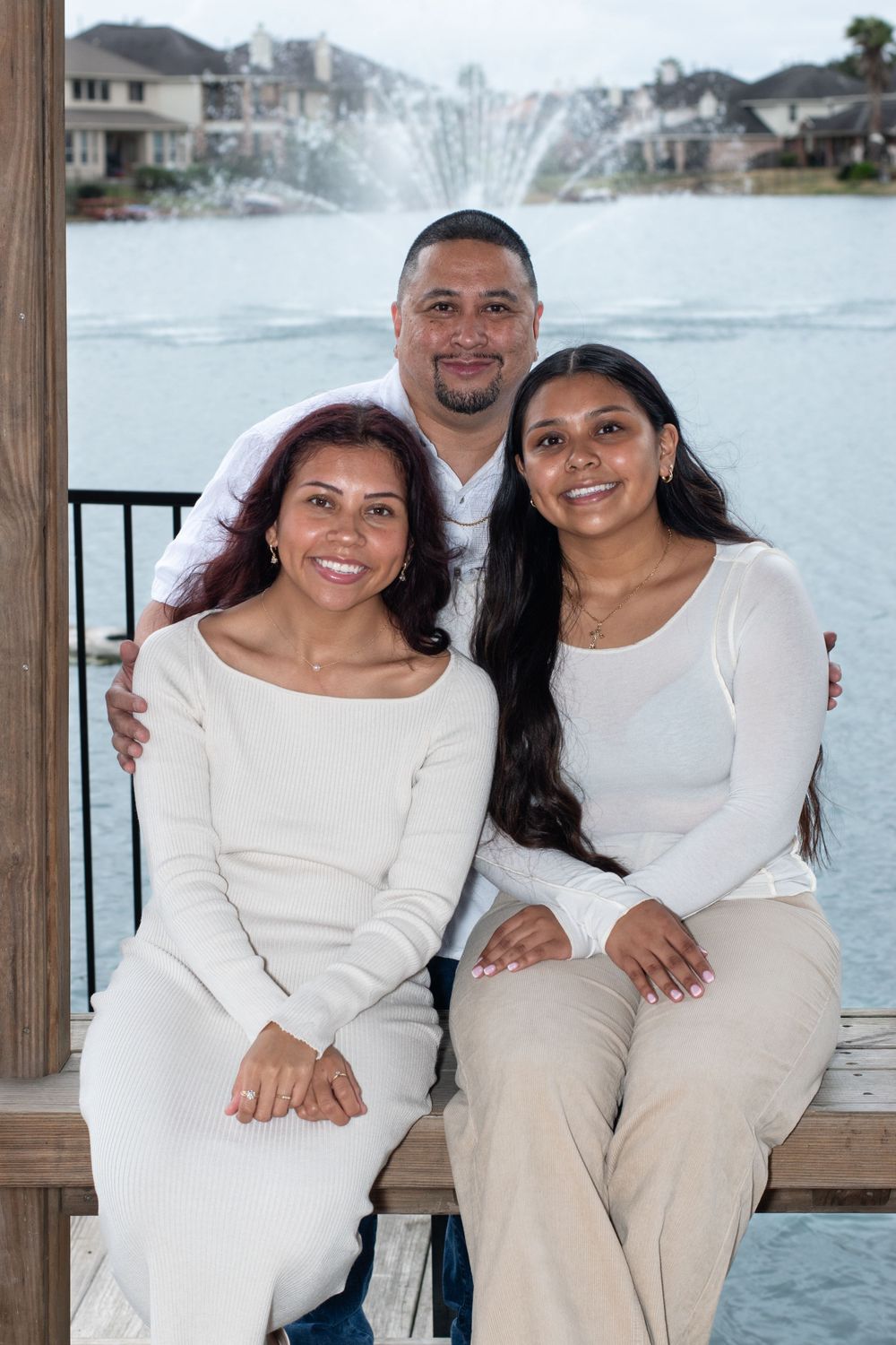 A family photo overlooking a waterfront fountain wearing matching white and beige outfits.