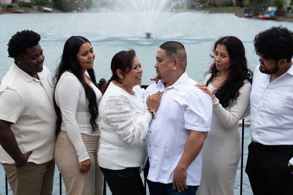 A group in coordinated cream and white outfits gathered by a fountain.