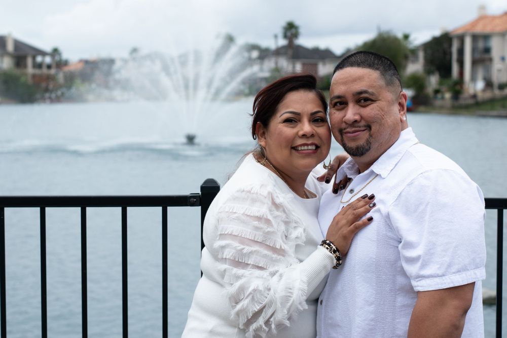 A couple shares an intimate moment by a lakeside fountain.