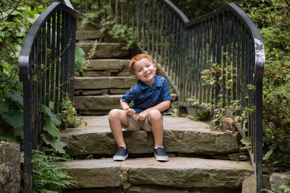 child being silly while sitting on steps at longwood gardens