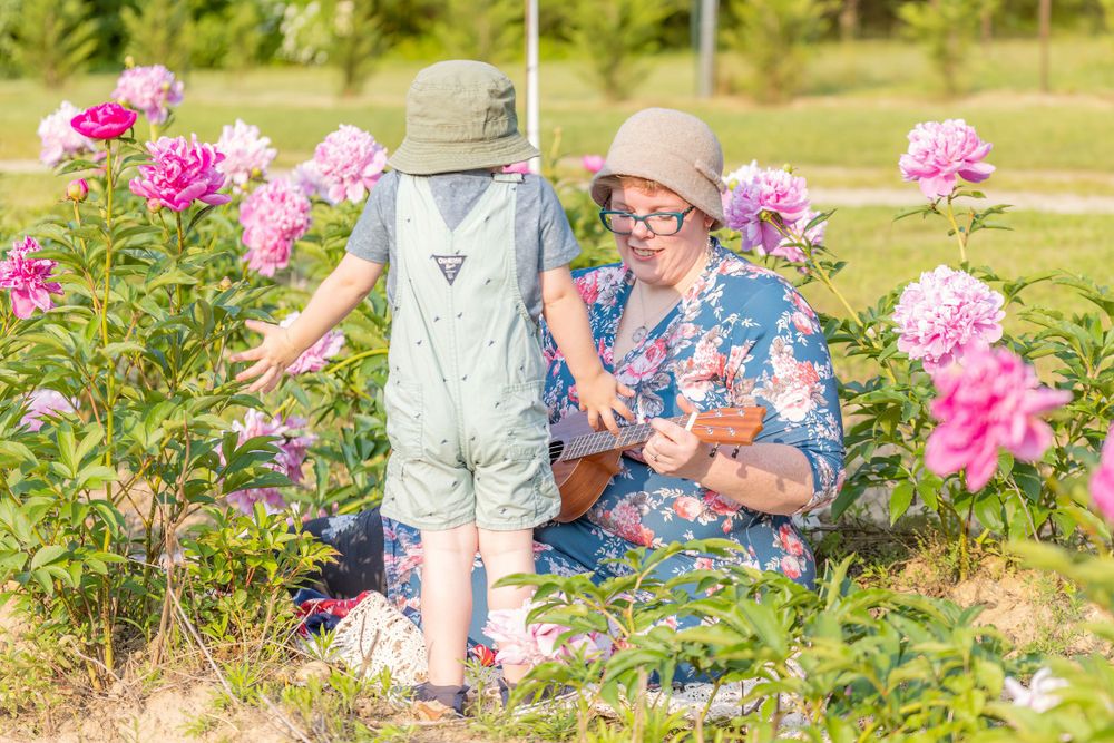 child shrugging shoulders at mom in peony field at turkey trac farms in millville new jersey cumberland county