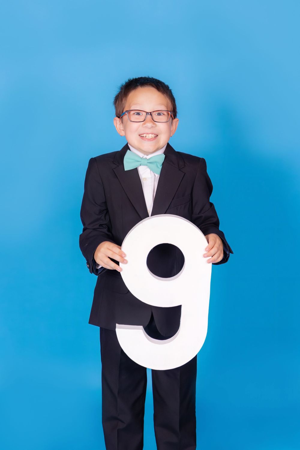 child making silly face while holding a 9 on blue jay savage paper backdrop in studio in clayton new jersey Gloucester