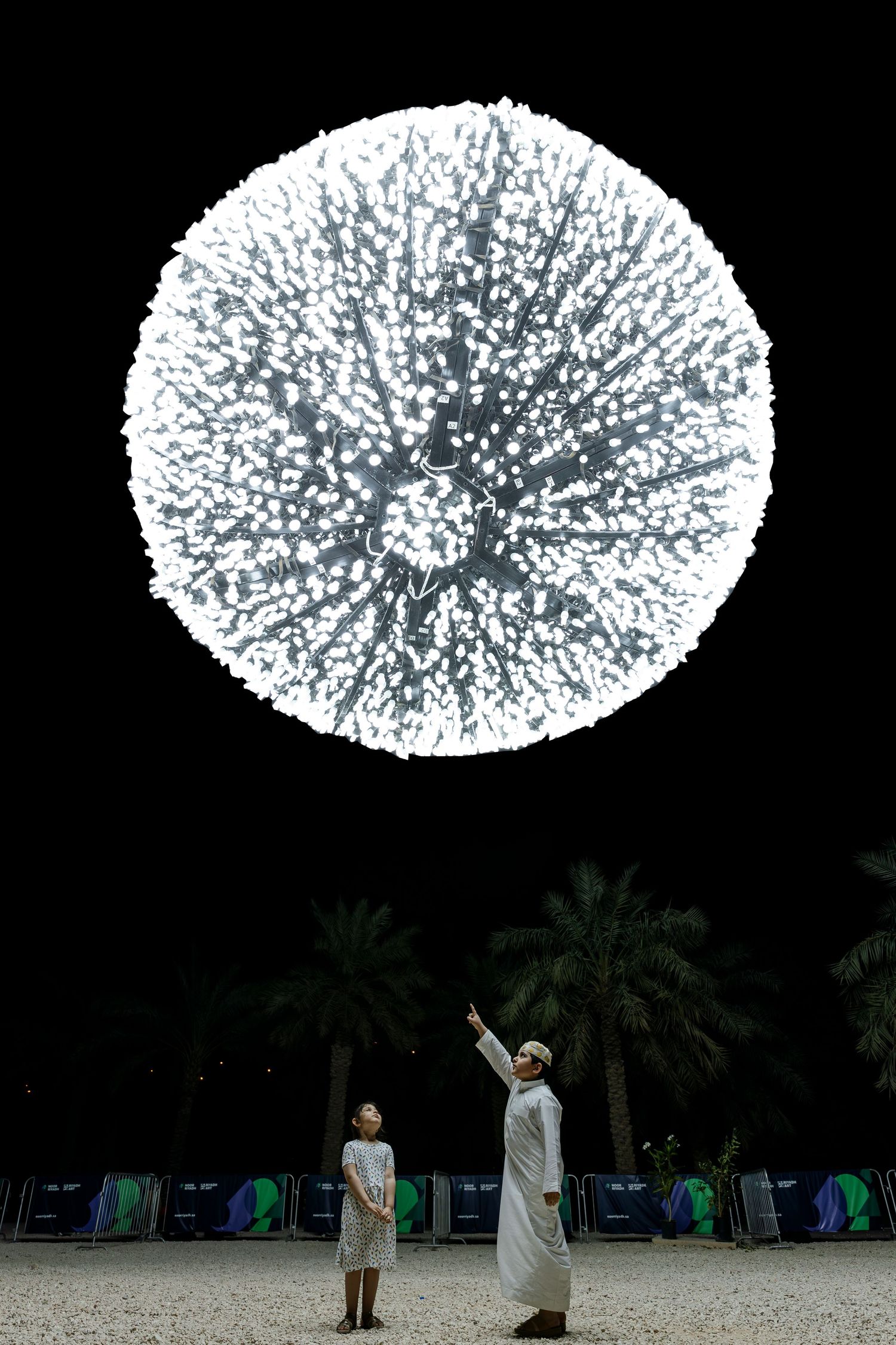 Large illuminated sphere display with spectators viewing from below at night.