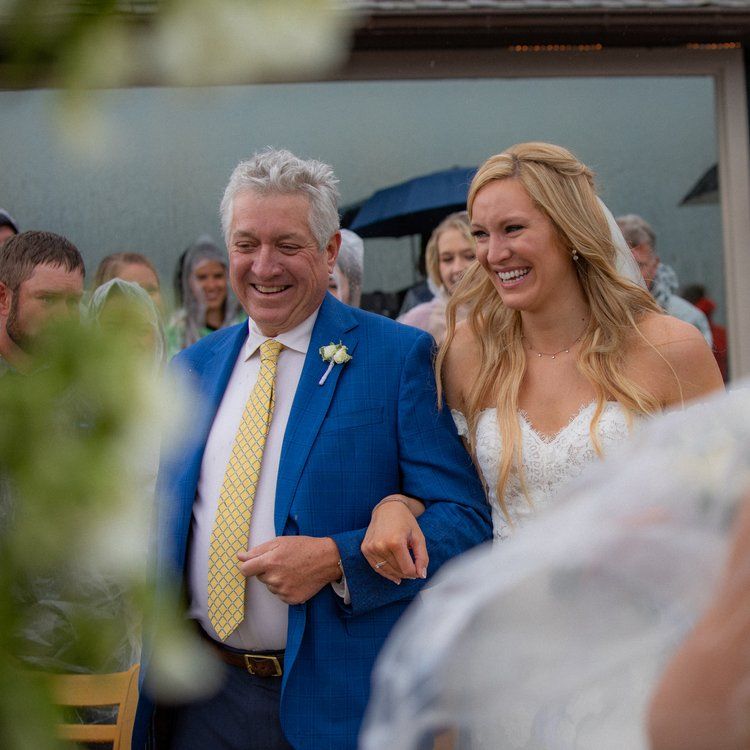 Two people walking down the aisle at an outdoor wedding celebration.