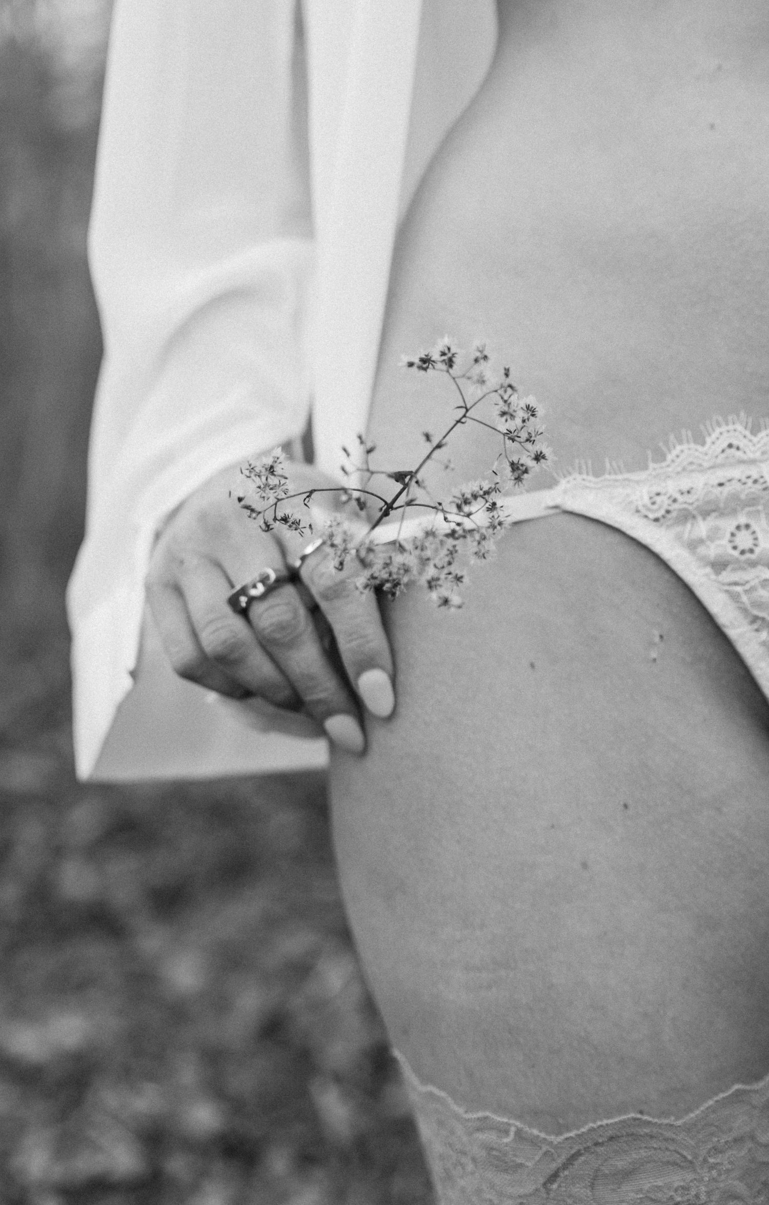 A black and white artistic photo series showing delicate flowers held against a pregnant belly.