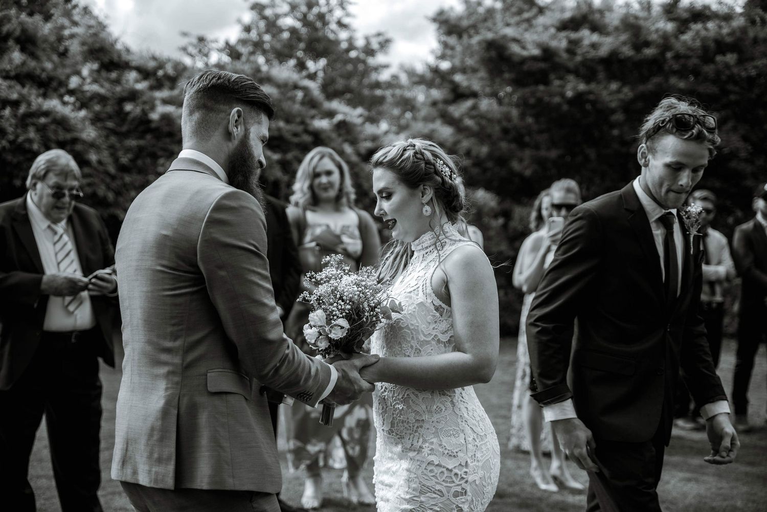 Wedding ceremony moment with guests watching in an outdoor garden setting.