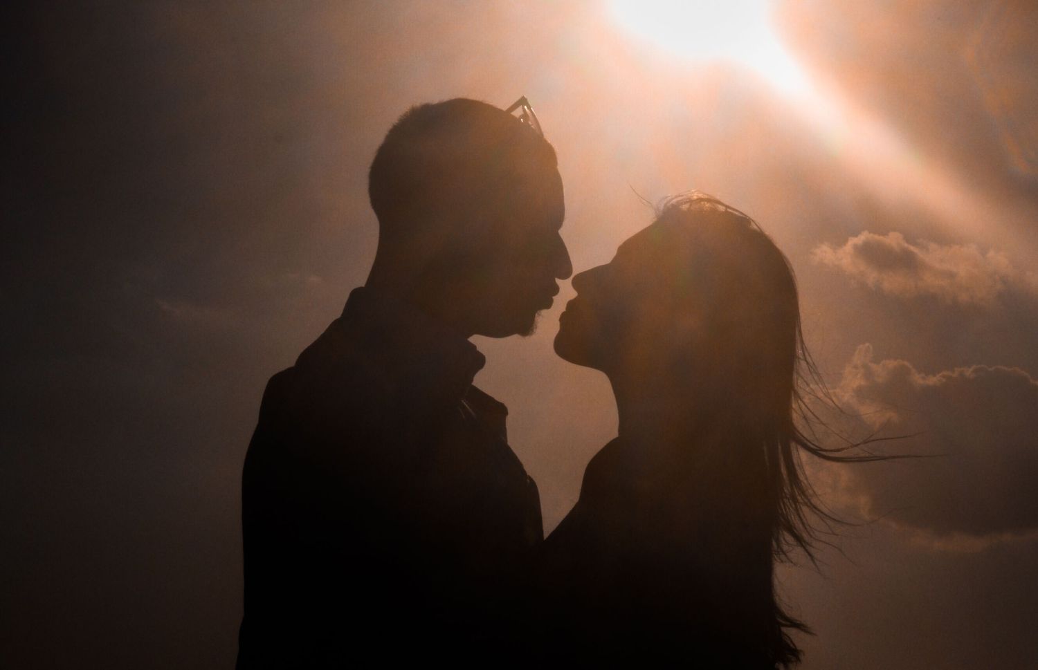 Silhouettes of couple against dramatic sunset sky.